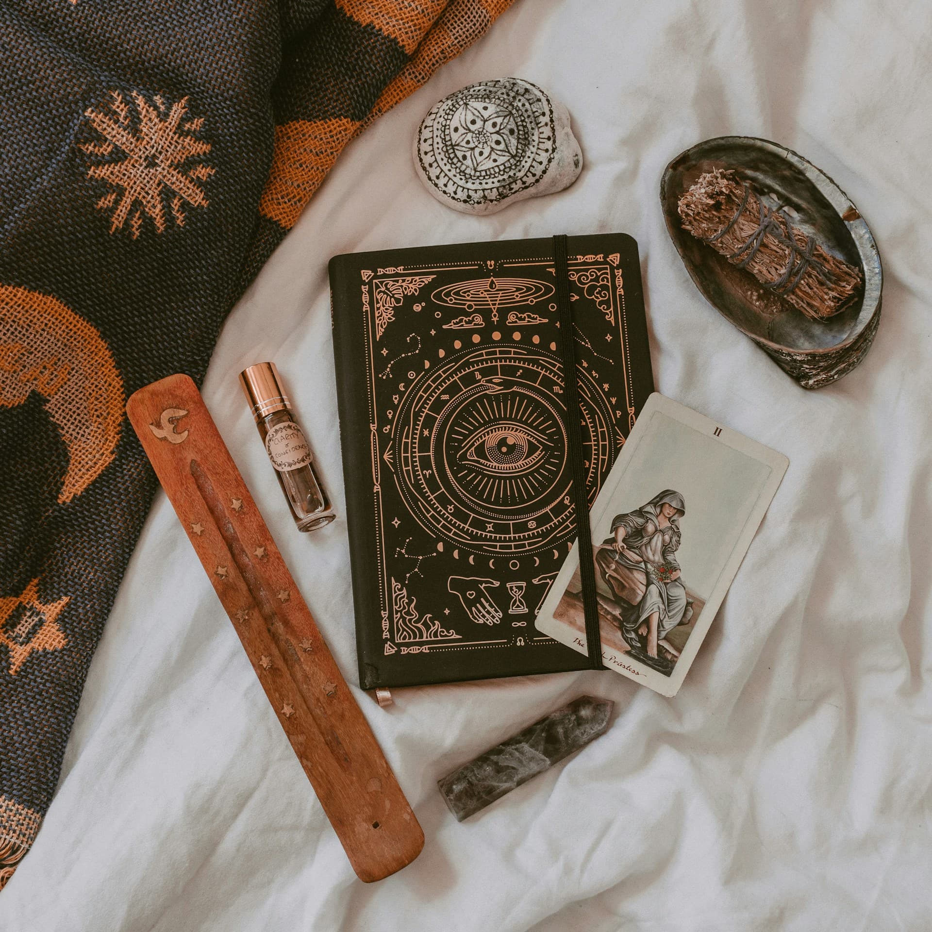 Spiritual objects including a notebook, incense, and a card on a cloth, representing spiritual coaching.